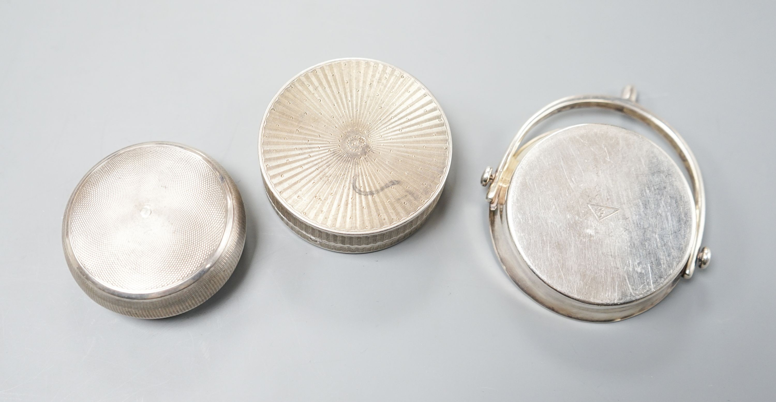 An early 20th century French engine turned white metal compact, 55mm, a similar circular box and embossed cover by Charles Barrier and a similar small dish with stirrup handle by Hermes.